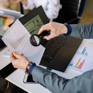 Adatdiagramok vizsgálata nagyítóval egy laptop fölött az irodában